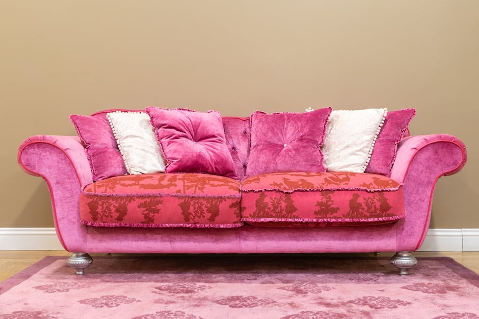 Close-up of two decorative throw cushions placed on an upholstered armchair with ornate, floral-patterned fabric in a warm beige color. One cushion features a vibrant floral tapestry design with roses
